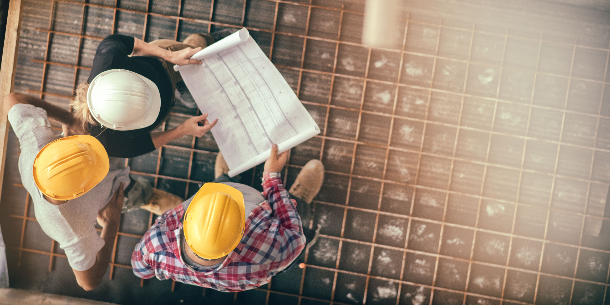 Three construction workers look at blueprints